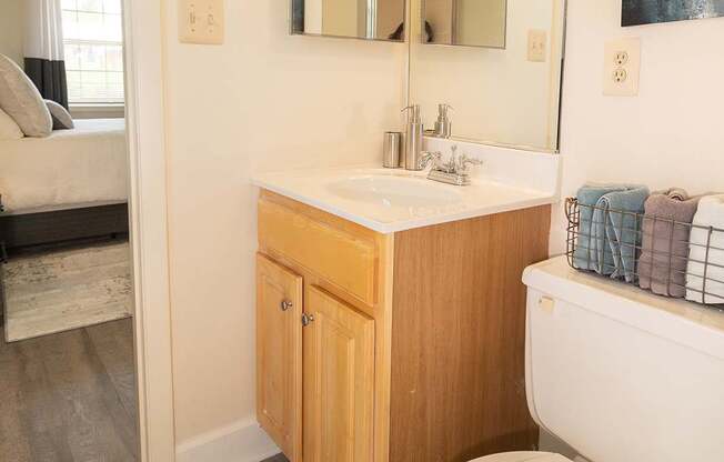 A bathroom with a toilet, sink, and mirror.