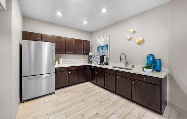 A kitchen with a refrigerator, sink, and cabinets.