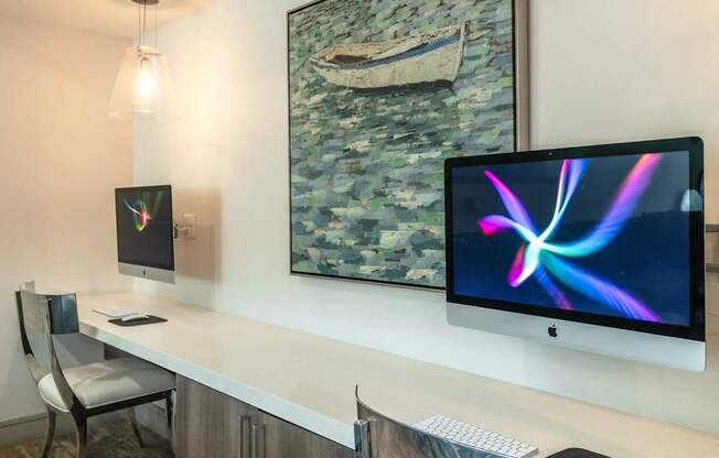 A modern workspace with a large monitor, keyboard, and a painting on the wall.