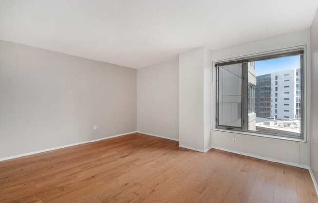 an empty living room with wood floors and a large window