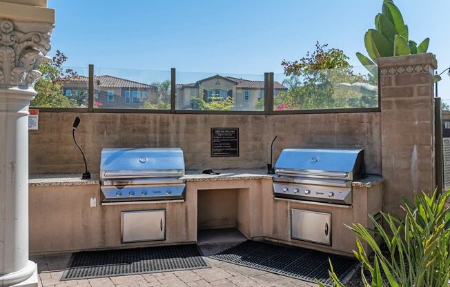 A stone wall with two built-in BBQ grills and a plaque on it.