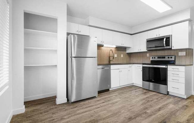 A kitchen with a refrigerator, oven, and microwave.