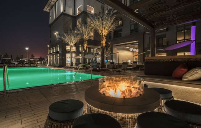 a fire pit in front of a pool at night