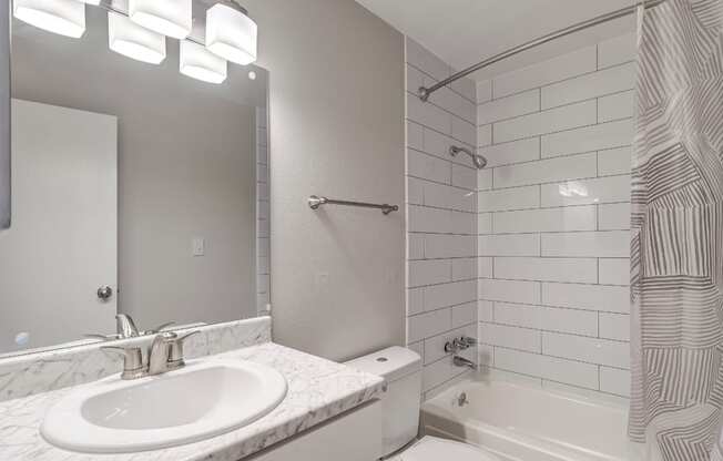 A white bathroom with a sink, toilet, and shower.