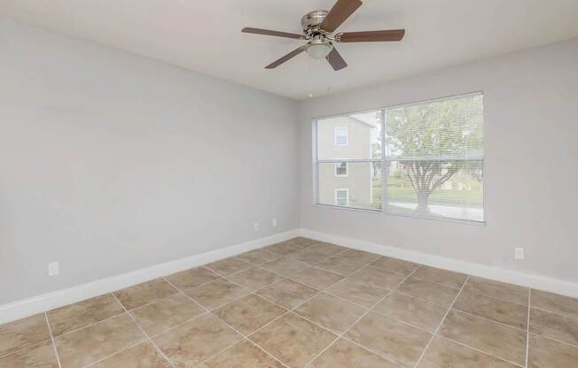 A room with a ceiling fan and tile flooring.