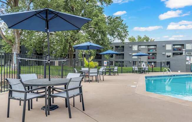 A pool area with a table and chairs and umbrellas.