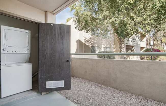 A washing machine is sitting in a small outdoor space.