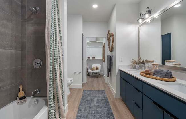 A bathroom with a white tub and a blue rug.