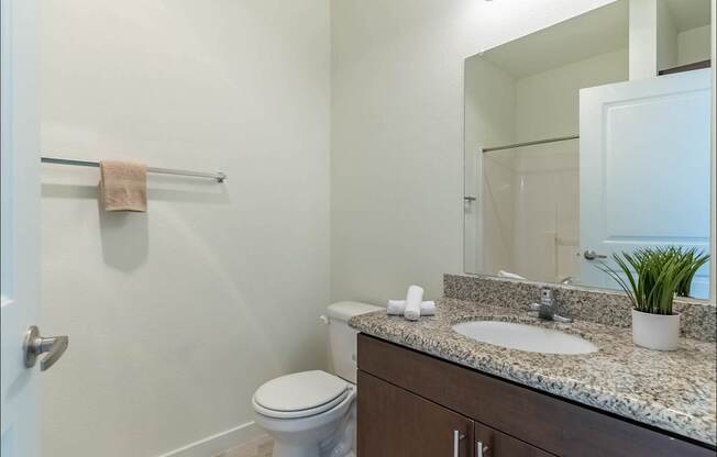 A bathroom with a toilet, sink, and mirror at Riverplace Apartment Homes, Independence, Oregon