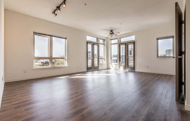 A spacious room with wooden floors and large windows.