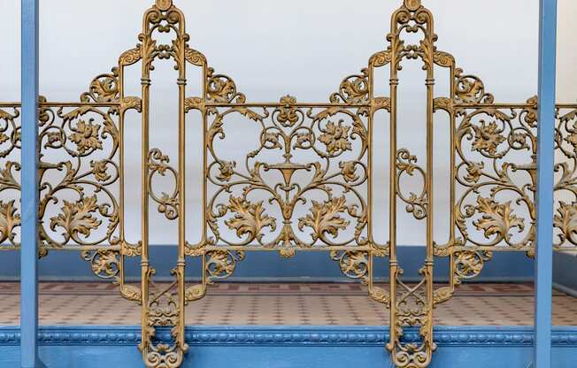 an ornate metal bed frame with gold filigree and blue at Residences at South High, Pittsburgh, PA ? 