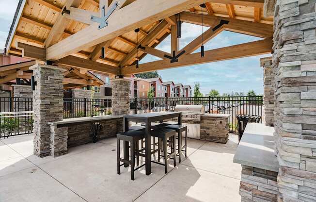 A patio with a table and chairs under a wooden roof.