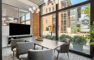 a dining room with a large window and a table with chairs and a television