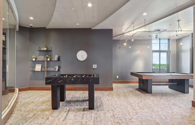 A clubroom with pool table and shuffleboard table and a window