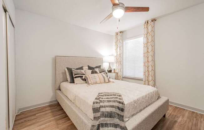 A bedroom with a bed, pillows, and a ceiling fan.