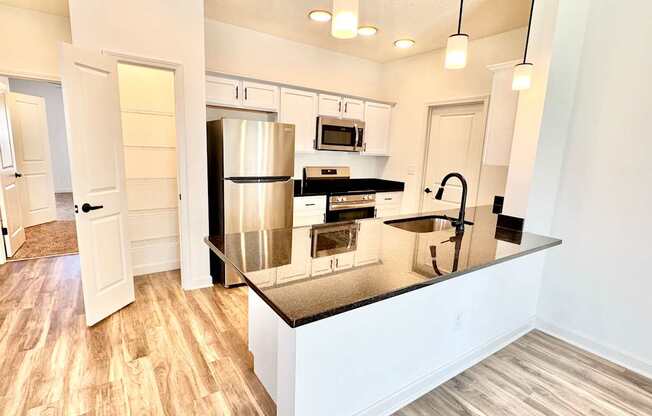A kitchen with a stainless steel refrigerator and a black countertop.