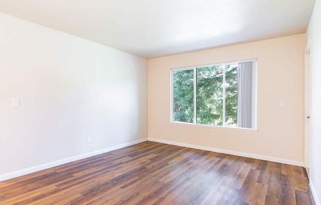 Empty room with wooden floors and a window.