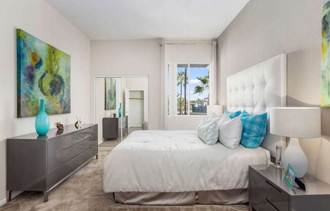 A bedroom with a large bed, a dresser, and a painting on the wall.