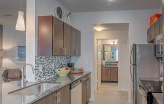 A kitchen with a refrigerator on the right and a sink on the left.