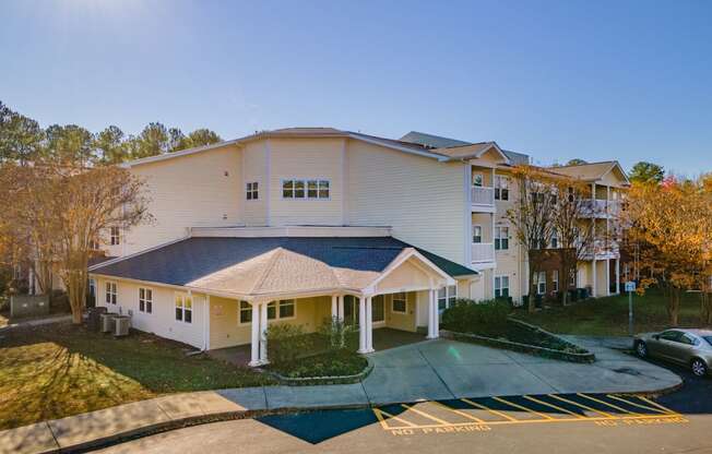 a large white building with a blue roof and a parking lot in front of it