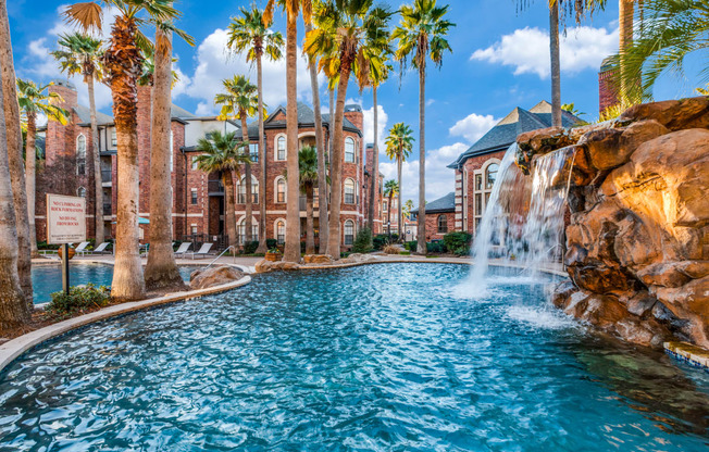 a swimming pool with a waterfall and palm trees