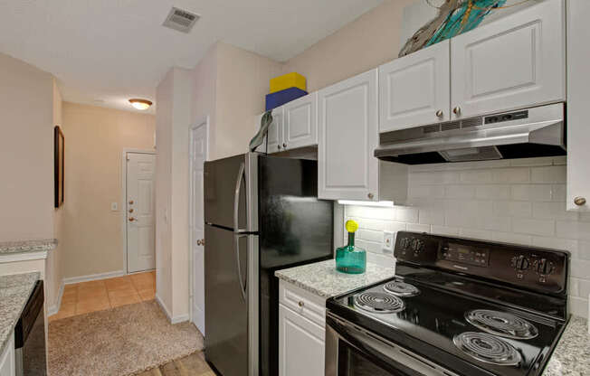 A kitchen with a black stove top oven and a black refrigerator.