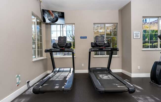 two treadmills in an indoor gym area with windows