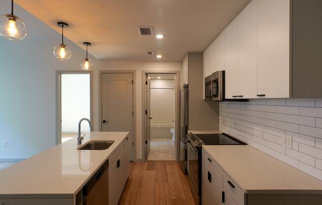 a kitchen with white counters and white cabinets and a door to a hallway at The Commonwealth Building, Pittsburgh, 15222