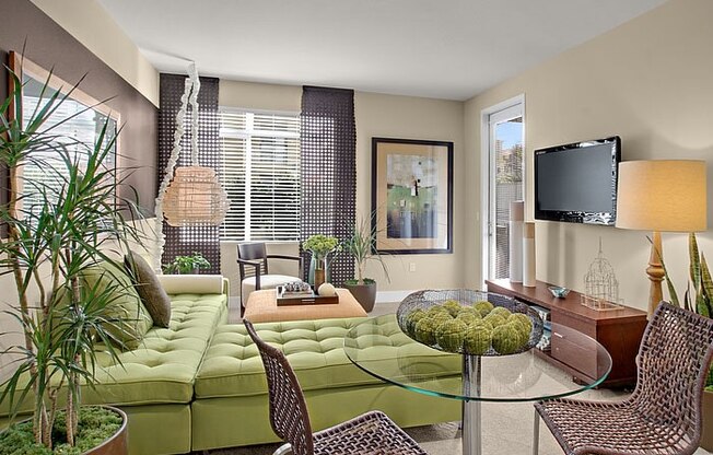 a living room with a green couch and a glass table