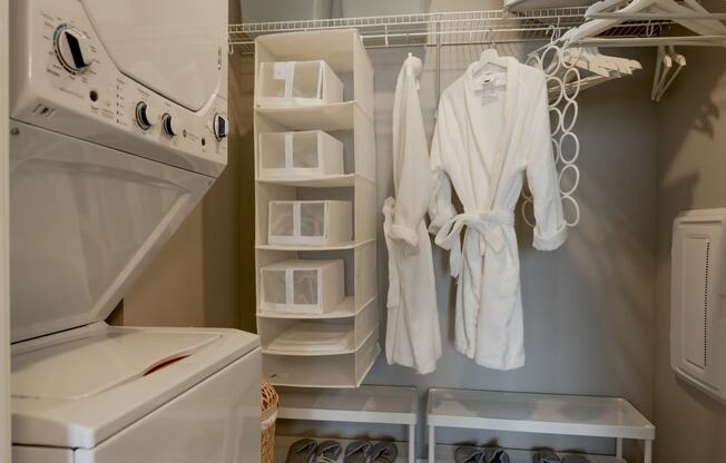 a small laundry room with a washer and dryer and a closet with robes at One Foundry Way, Missouri