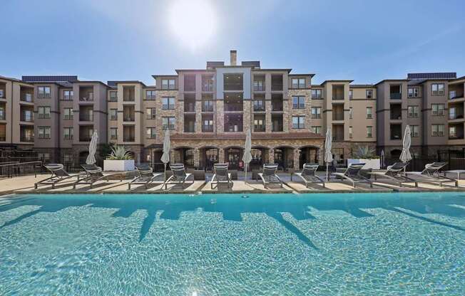 A large swimming pool in front of apartment buildings.