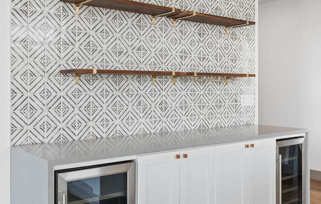 a living room with white cabinets and a wall with a white and white geometric wallpaper