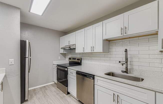 A kitchen with white cabinets and a black refrigerator.