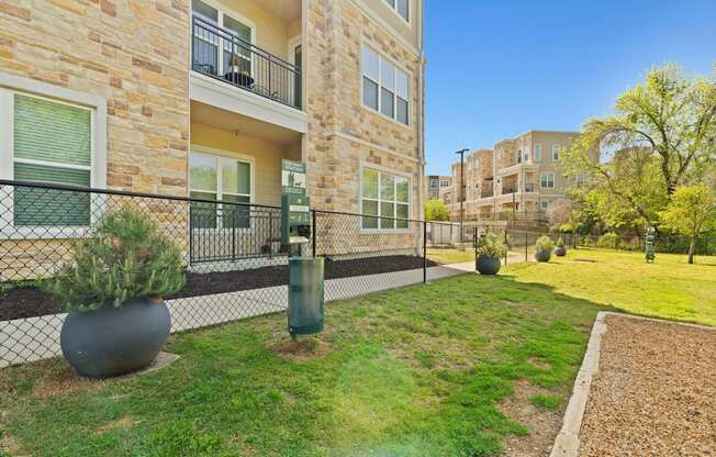 A large grey pot sits on a grassy area in front of a building.