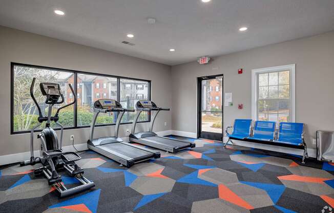 A gym with treadmills, elliptical machines, and a bench.