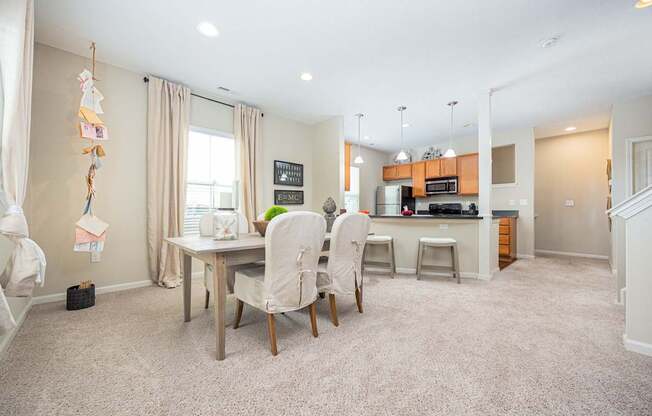 A kitchen with a dining table and chairs in the middle of the room.