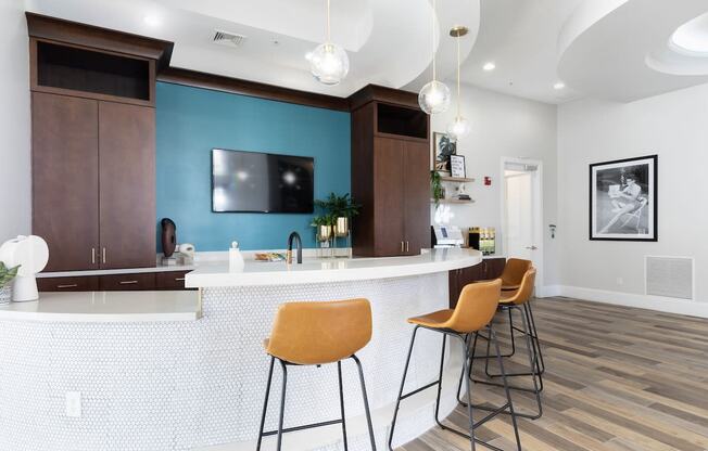a kitchen with a bar and stools and a blue wall