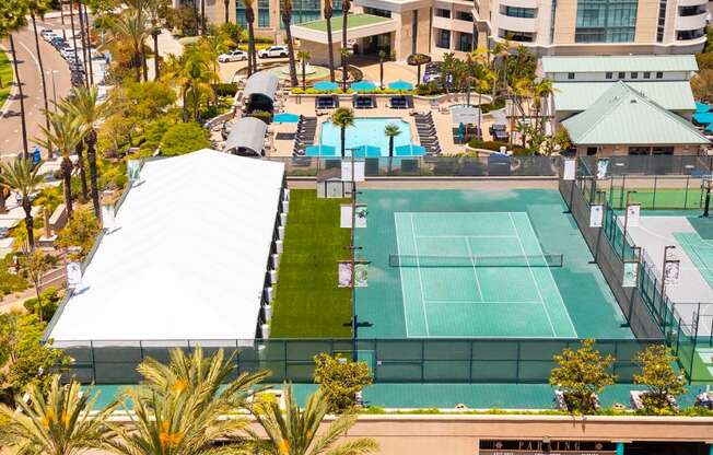 Tennis court surrounded by palm trees and buildings. at Towers at Costa Verde Apartments, San Diego, 92122