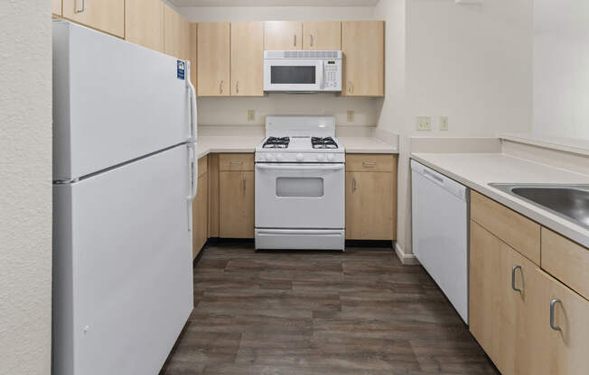 A kitchen with a white refrigerator, stove, microwave and dishwasher. at Fieldstream Apartment Homes in IA 50023