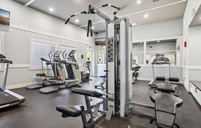A gym with a variety of equipment including treadmills, weights, and exercise machines.