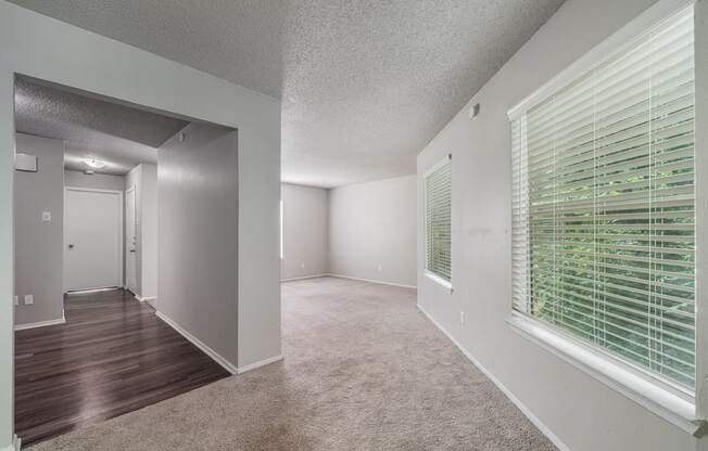 the spacious living room and dining room of an apartment with a large window  at Shadow Ridge, Arlington, 76013