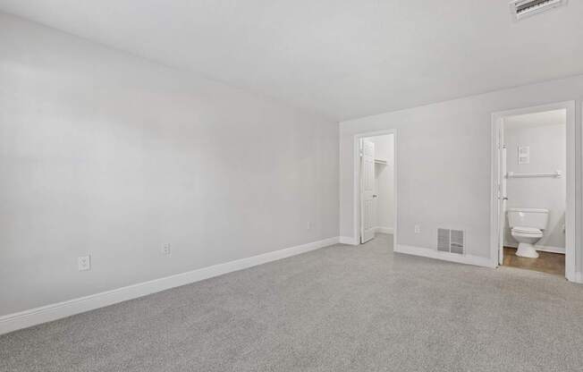 A white room with a carpeted floor and a toilet in the corner.