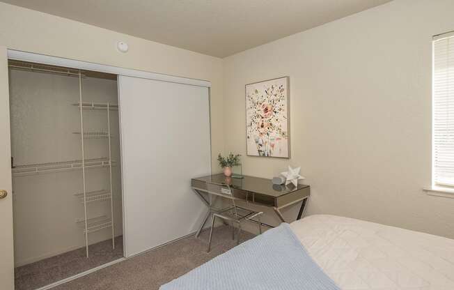 A bedroom with a bed, desk, chair, and a painting on the wall at Zinfandel Village Apartments, California, 95670