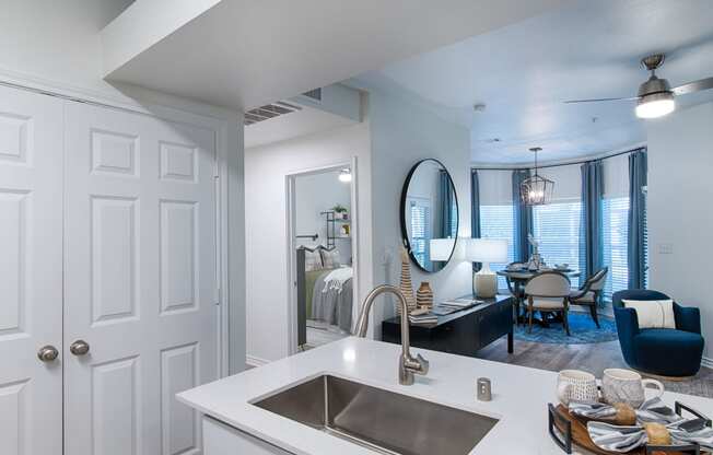 a kitchen sink with a view of a living room and dining room in the background