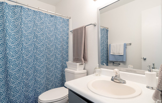 A bathroom with a white sink and a blue shower curtain.
