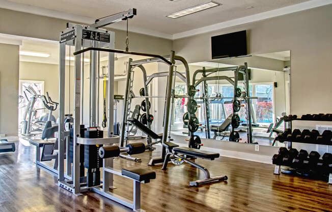 a gym with cardio machines and weights on a wooden floor