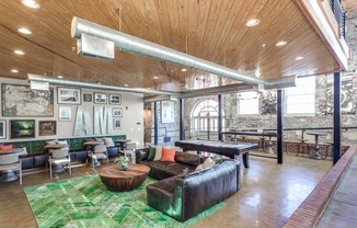 View of Resident Lounge, Showing Seating Area, Pool Table, and Mill Architecture at Alpha Mill Apartments