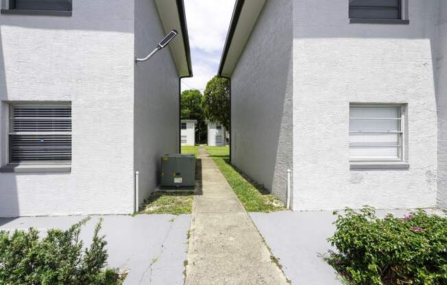 an alley between two white buildings with a green mailbox