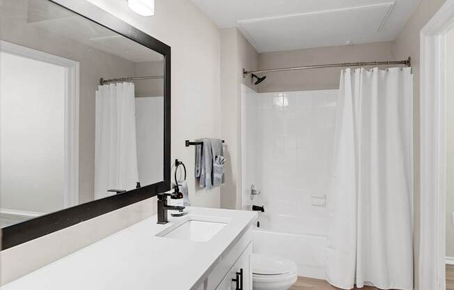 Full bathroom with wide vanity, framed mirror, and tub-shower combination.