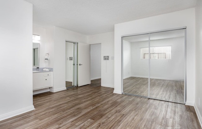 an empty bedroom with a mirrored closet and a bathroom